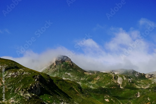 green mountains and white soft fog on the peaks with blue sky