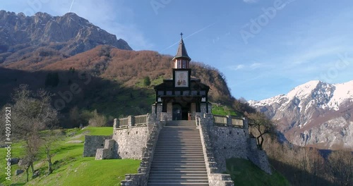 Drone aerial view of memorial church of the Holy Spirit in Slovenia. Beautiful Alps mountains and green meadows. Javorca is symbol of a call for reconciliation. Ascending