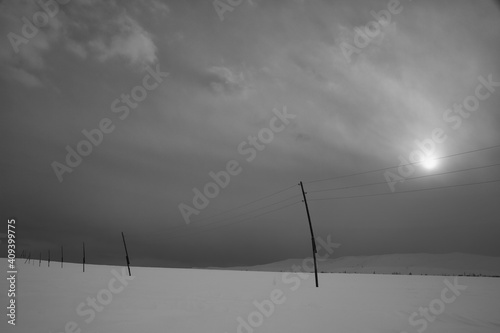 Strong winter black and white landscape with clouds and electric pillars