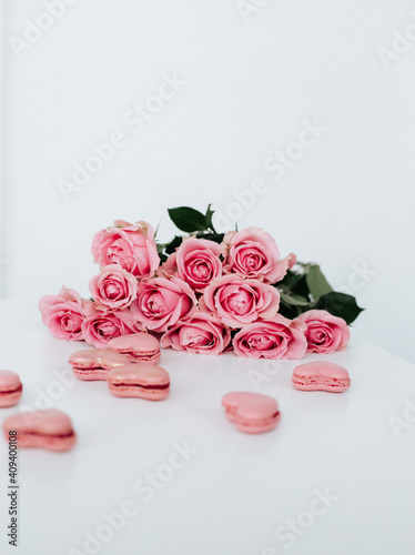 Pink roses on a white surface with pink heart shaped macaroons for wedding