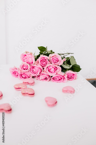 Pink roses on a white surface with pink heart shaped macaroons for mothersday 