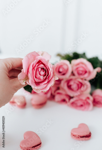 Pink roses on a white surface with pink heart-shaped macaroons for birthday