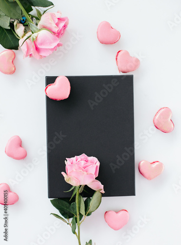 Black gift box surronded with heart shaped macaroons and pink roses