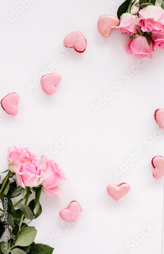 Pink macaroons on a white background with pink roses for holidays