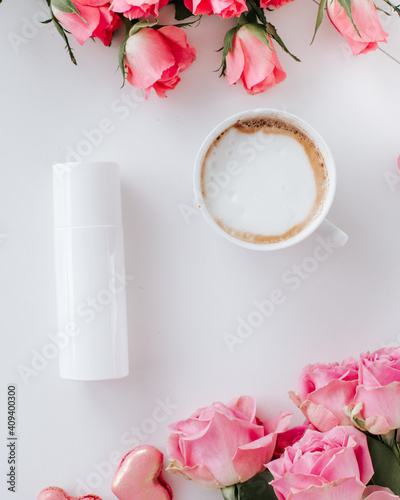 White skincare bottle with coffee cup and roses white background