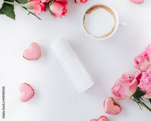 White skincare bottle with coffee cup and roses white background
