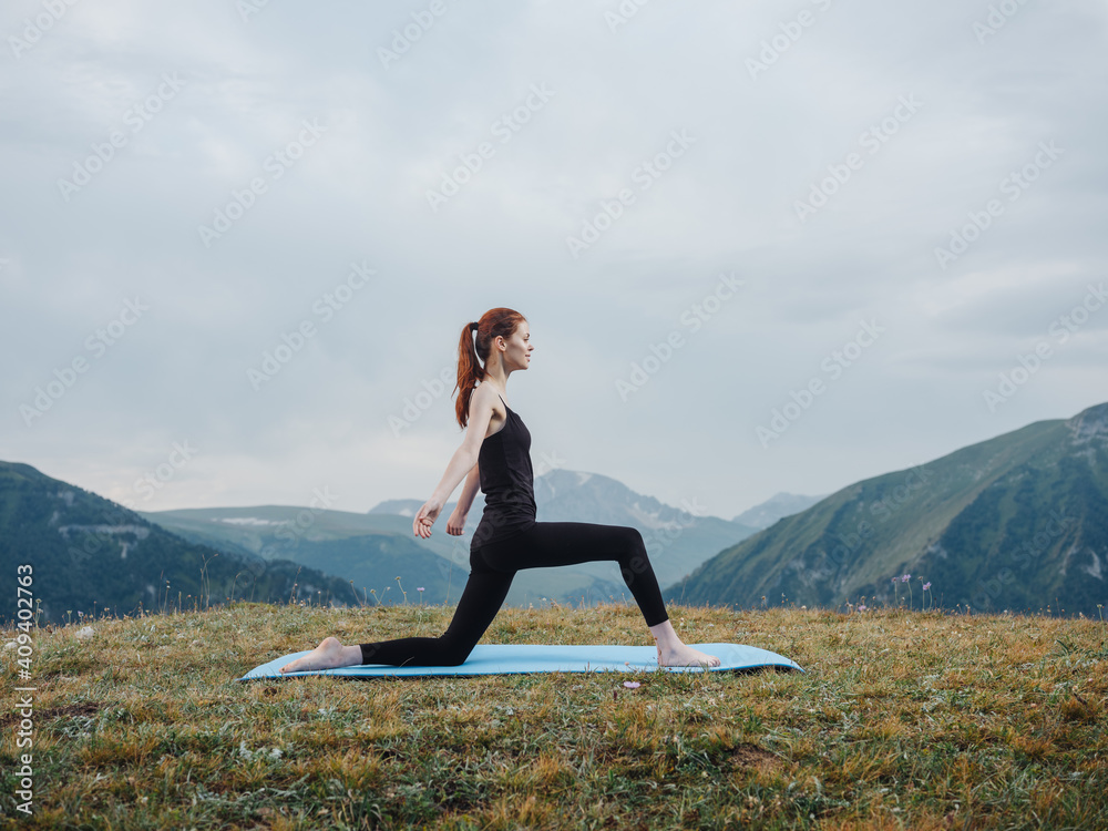 Woman practices yoga on a rug outdoors in the mountains fresh air tourism Woman practices yoga on a rug outdoors in the mountains fresh air tourism