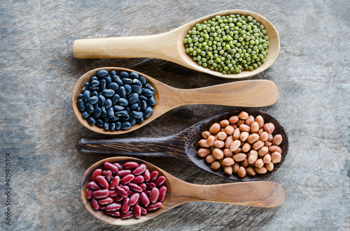 Four kinds of natural cereal and grain seeds consisted of black and red bean, mung, and peanut in wooden spoon on grunge background
