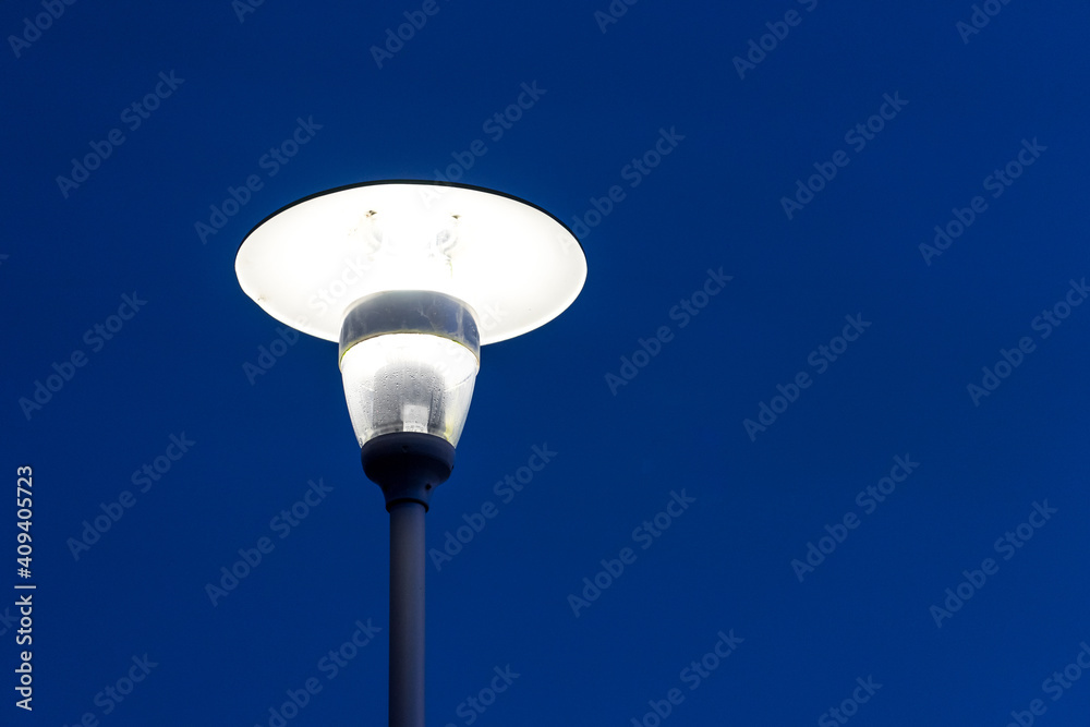 Bright glowing street lamp against the dark blue sky Bright glowing street lamp against the dark blue sky