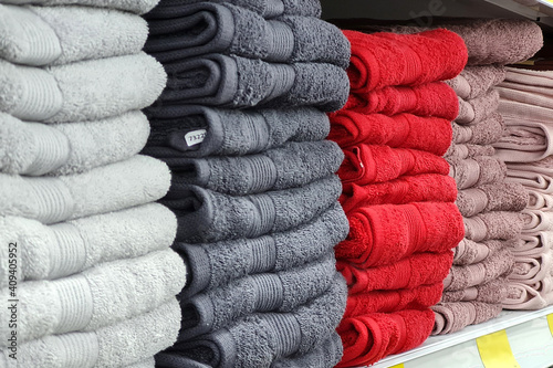 Stacks of beautiful white, gray, red towels sells on a showcase in the store.