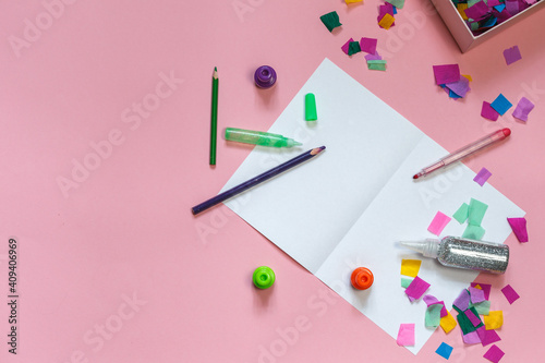 The layout on a pink background, making greeting cards out of paper, coloured confetti, glitter and pencils. Top view with space