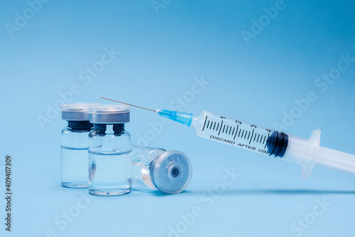 Ampoule, vial bottle, syringe on blue background. Vaccination concept, disease prevention. Health care, Coronavirus vaccine development