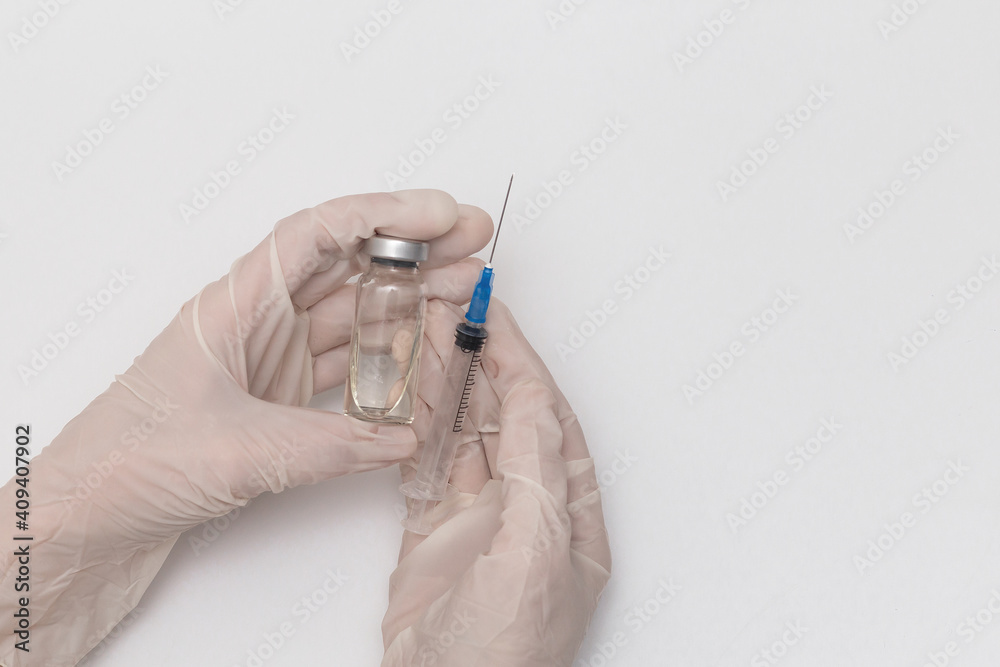 Close-up of a doctor's hands with a bottle and a vaccine, Medical concept vaccination subcutaneous injection treatment, prevention. On a white background. Vaccination against coronavirus Close-up of a doctor's hands with a bottle and a vaccine, Medical concept vaccination subcutaneous injection treatment, prevention. On a white background. Vaccination against coronavirus