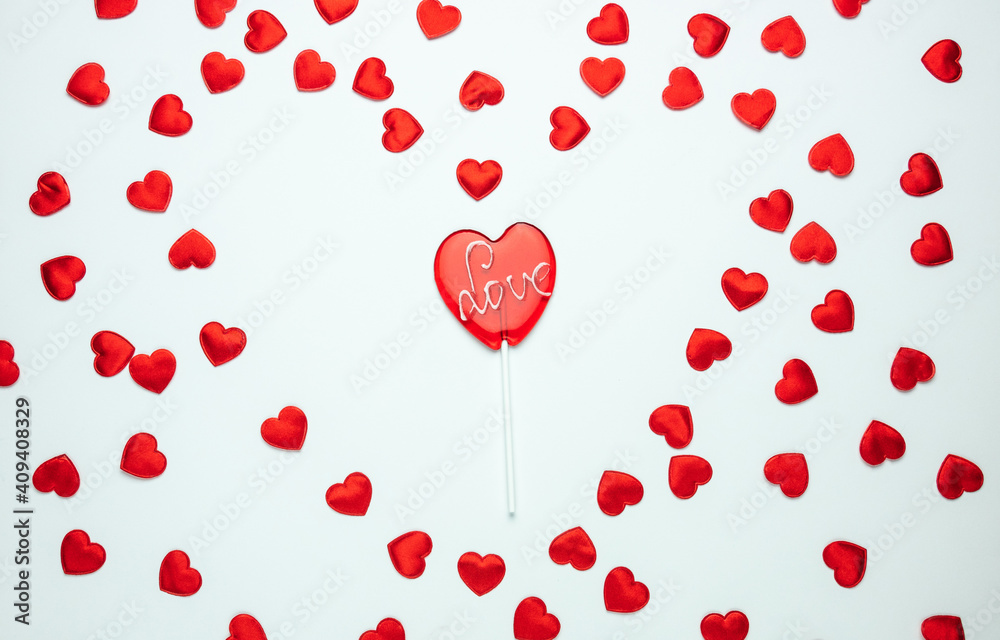 Heart shaped lollipop with Love inscription. Flat lay composition for Valentine's Day, birthday, anniversary or wedding. With decorative hearts on white background.