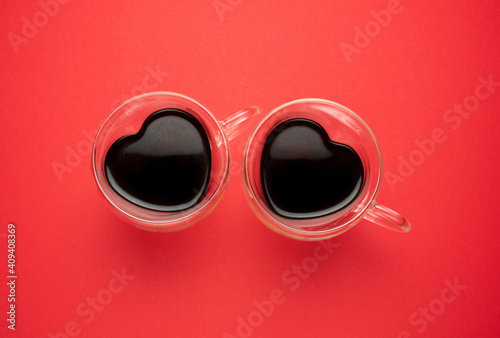 Two heart-shaped coffee mugs on red background. Flat lay composition for Valentine's Day, birthday, anniversary or wedding.