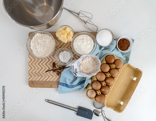 Top view of kitchen equipment with flour, cocoa powder, eggs, and butter for baking a cake photo