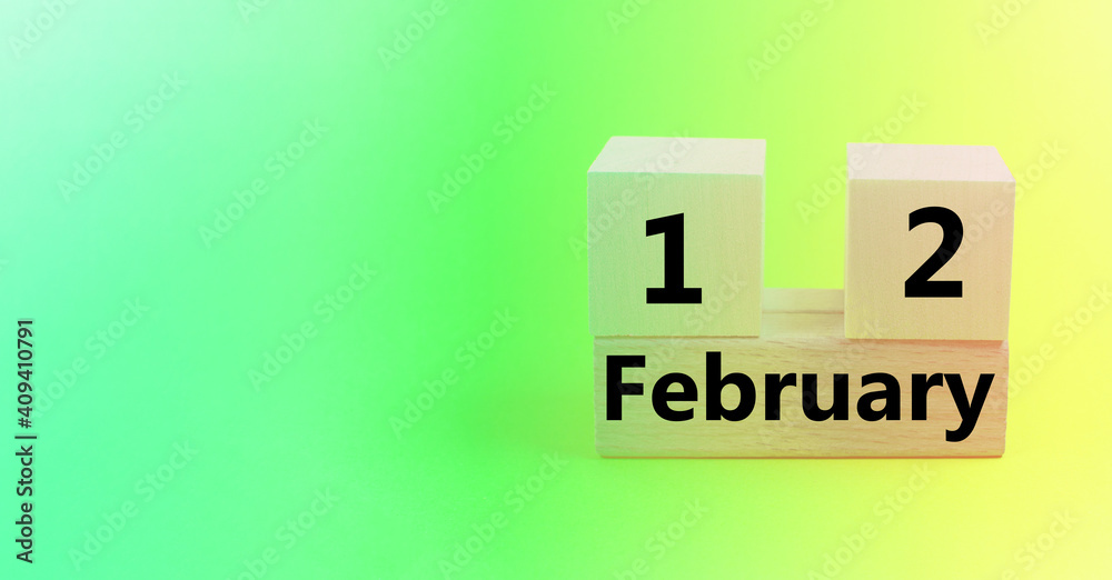 Calendar for February 12 on a wooden cube, gradient yellow-green background, empty space for text, banner Calendar for February 12 on a wooden cube, gradient yellow-green background, empty space for text, banner