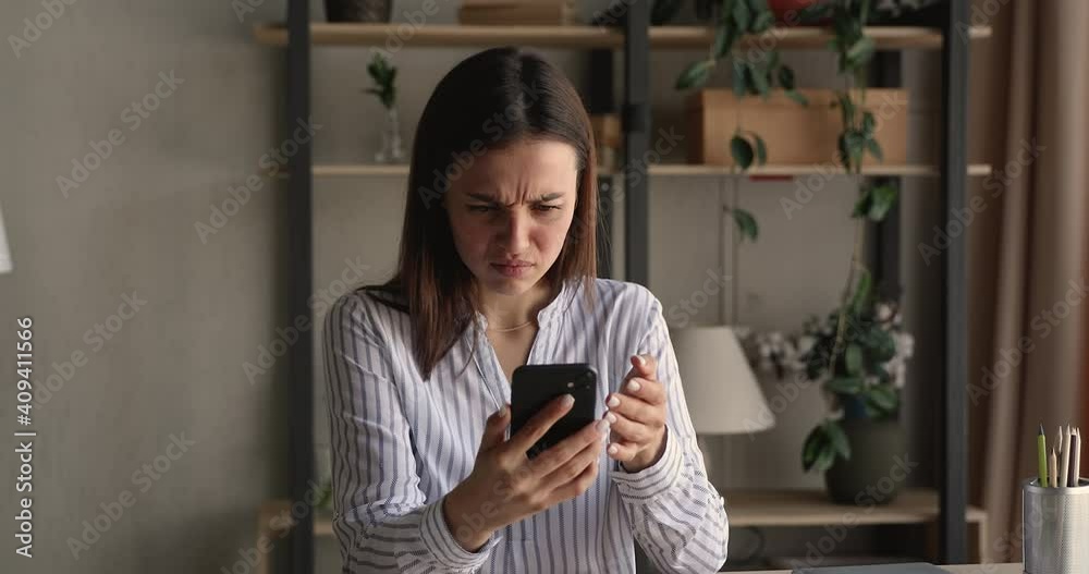 Stressed nervous young woman looking at cellphone screen, feeling frustrated of receiving message or email with bad news. Unhappy millennial female user dissatisfied with bad electronic device work.