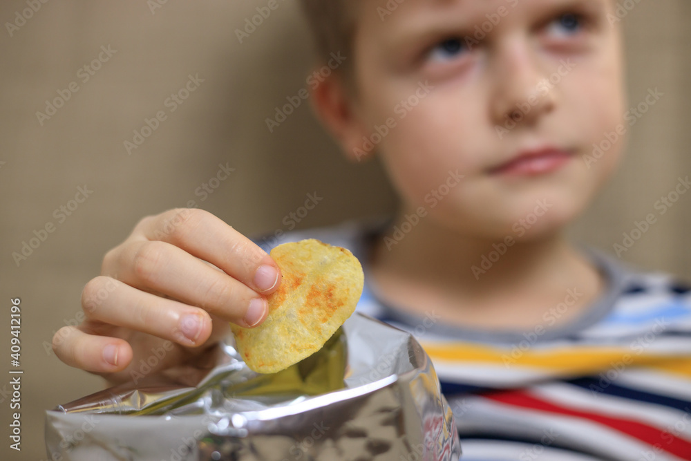 Little boy sitting on sofa, eating chips from packet Little boy sitting on sofa, eating chips from packet