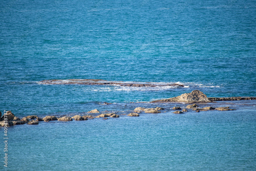 Fototapeta premium Stones protrude from the blue sea