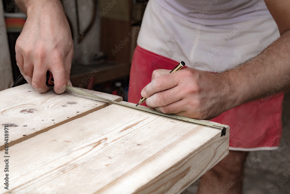 Male carpenter working with wood material in a garage. Male carpenter working with wood material in a garage.