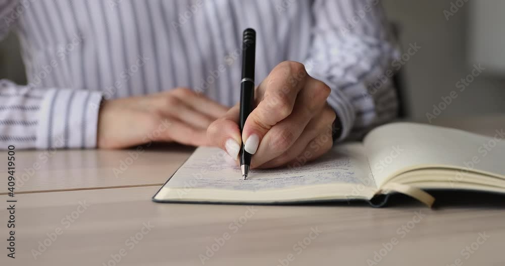 Close up young business lady writing notes in paper planner, managing tasks or optimizing working schedule, sitting at table. Skilled female student involved in learning or preparing for exam. Close up young business lady writing notes in paper planner, managing tasks or optimizing working schedule, sitting at table. Skilled female student involved in learning or preparing for exam.