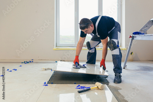 A male construction worker installs a large ceramic tile