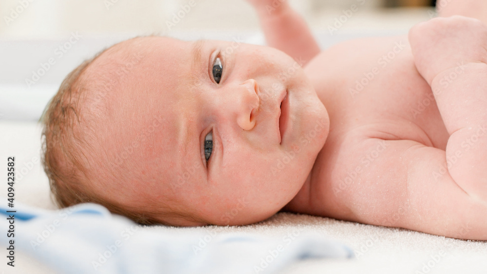 Closeup portrait of cute little newborn baby boy lying on changing table. Concept of babies and newborn hygiene and healthcare. Caring parents with little children. Closeup portrait of cute little newborn baby boy lying on changing table. Concept of babies and newborn hygiene and healthcare. Caring parents with little children.