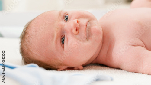 Portrait of unhappy crying newborn baby lying on changing table