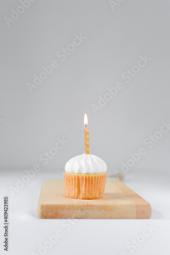 Cupcake with a white frosting and a gold lit candle  birthday cupcake with a candle