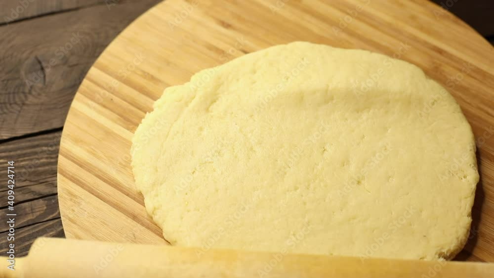 woman prepares dough for baking, rolls out on a wooden board, hands close-up, process of cooking woman prepares dough for baking, rolls out on a wooden board, hands close-up, process of cooking