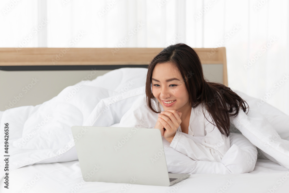 Young female lying on bed using notebook computer. Happy female using laptop at home in bedroom. Working from home in quarantine lockdown. Women watching movie on laptop lying in bed. Young female lying on bed using notebook computer. Happy female using laptop at home in bedroom. Working from home in quarantine lockdown. Women watching movie on laptop lying in bed.