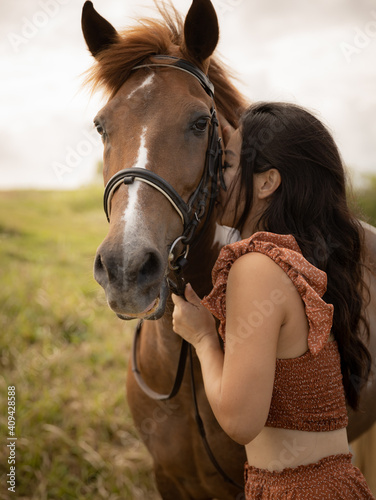 Portrait of Asian woman and brown horse. Woman hugging and kissing horse. Romantic concept. Love to animals. Nature concept. Bali, Indonesia