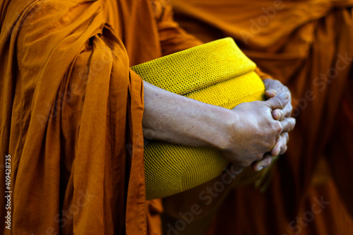 Fototapet hand of monk dressing orange robe, holding bowl during reception of alms, around