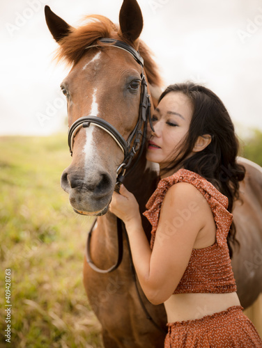 Portrait of Asian woman and brown horse. Woman hugging and kissing horse. Closed eyes. Romantic concept. Love to animals. Nature concept. Bali, Indonesia