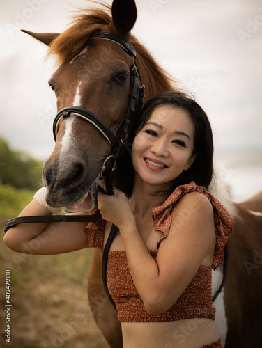 Portrait of smiling woman and brown horse. Asian woman hugging horse. Romantic concept. Positive emotions. Love to animals. Nature concept. Bali, Indonesia © Olga
