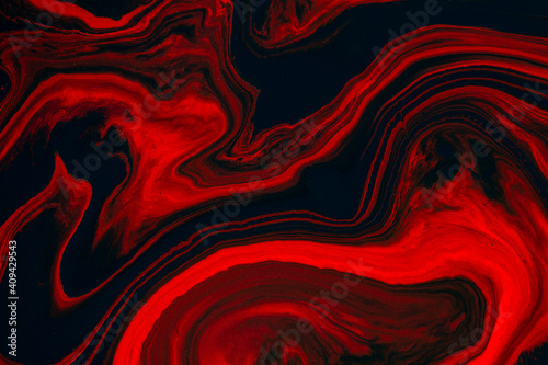 Fluid art texture. Abstract background with swirling paint effect. Liquid acrylic picture that flows and splashes. Mixed paints for baner or wallpaper. Black, red and orange overflowing colors