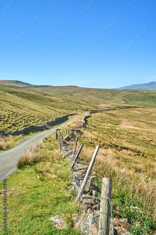 Remote, narrow moorland road in bleak and treeless hilly landscape