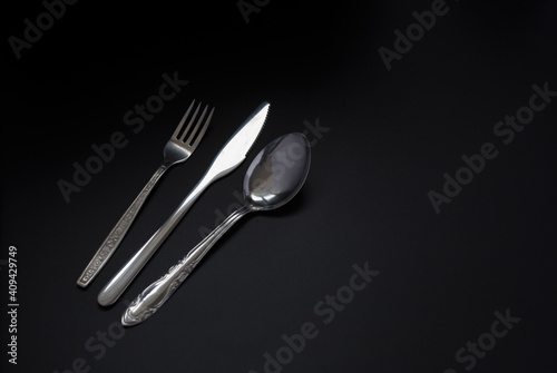 fork, spoon and knife on a dark background. Copy space
