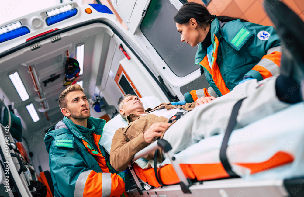 Serious and professional team of doctors in the ambulance moving on a patient into the hospital during an emergency situation. Serious and professional team of doctors in the ambulance moving on a patient into the hospital during an emergency situation.
