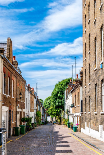 Wall Mural Residential street with red-brick houses and bushes of colorful flowers in Notting Hill area, west London, England, United Kingdom