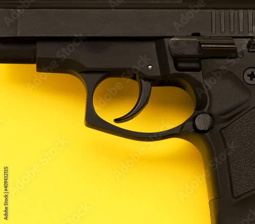 Metal trigger pistol on yellow background, top view