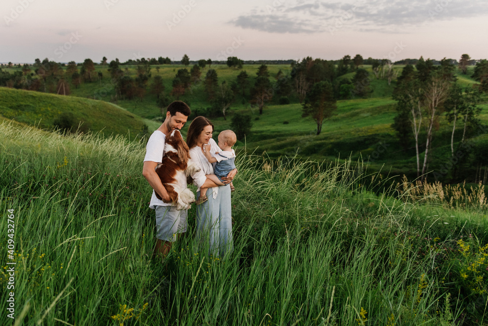 A young beautiful family with a little daughter and a dog hug, kiss and walk in nature. Photo of a family with a small child in nature. A young beautiful family with a little daughter and a dog hug, kiss and walk in nature. Photo of a family with a small child in nature.