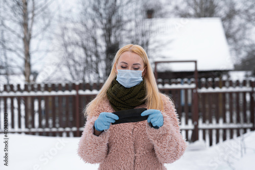 young girl, with a blue medical mask on her face, holds in her hands, in blue gloves, a second mask. Covid-19 new recommendations photo