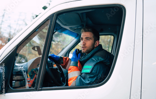 Professional and confident young man doctor looking on the camera with ambulance background