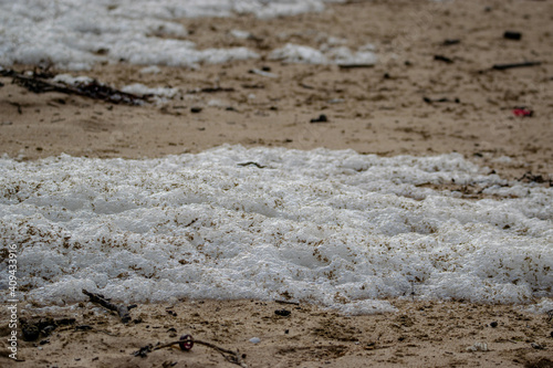 Vendée, France; January 23, 2021: sea foam, or seawater foam, covered a beach in Brétignolles Sur Mer, caused by the strong wind.