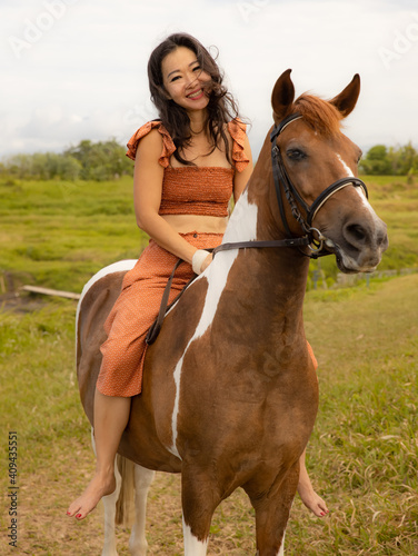 Happy smiling woman riding horse. Outdoor activities. Love to animals. Traveling concept. Bali