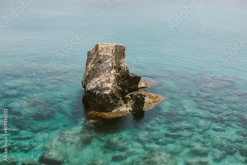 Beautiful seascape. Large stone in the middle of a transparent blue sea, stones are visible under the water.