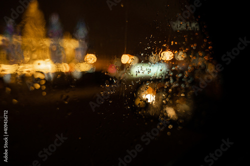 View of the night city through the wet car window with drops