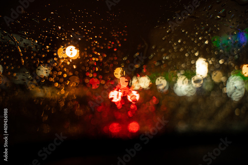 View of the night city through the wet car window with drops